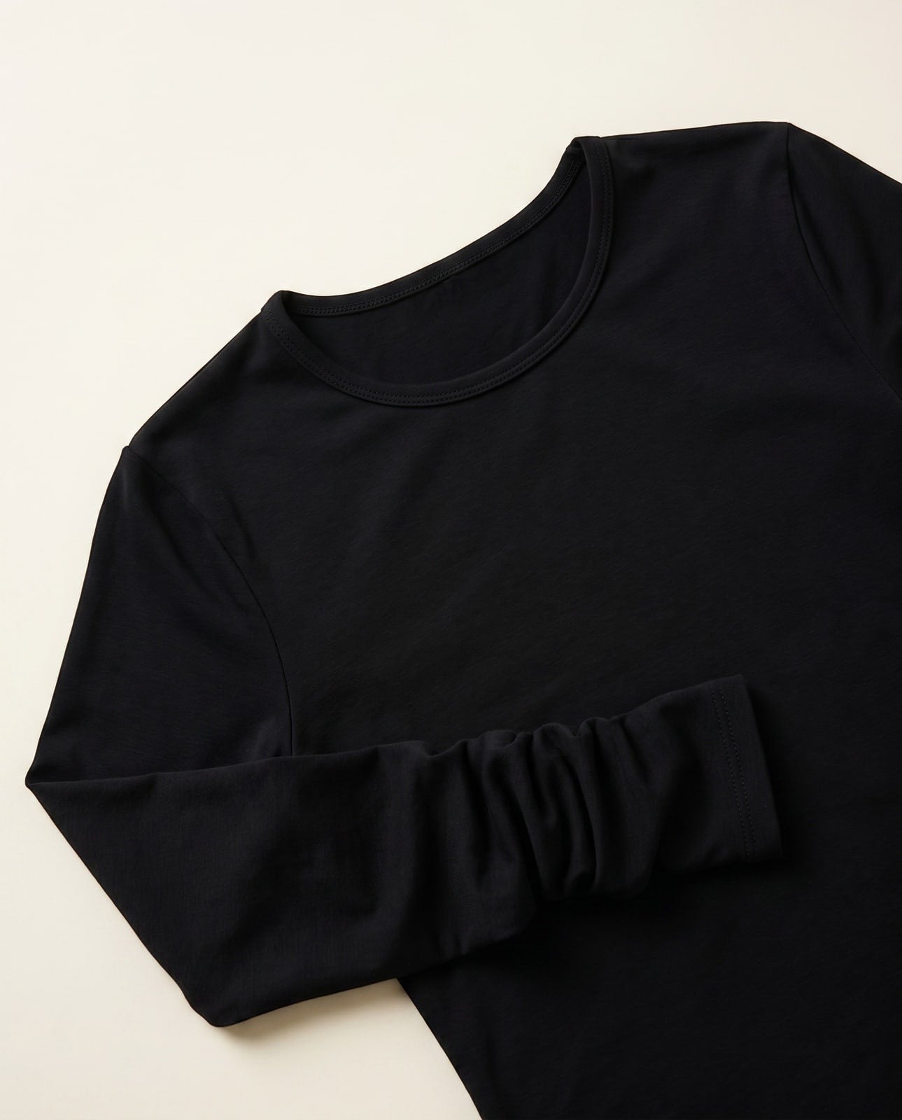 Joubify black long sleeve round-neck top in matte stretch jersey with ruched sleeves on a neutral background