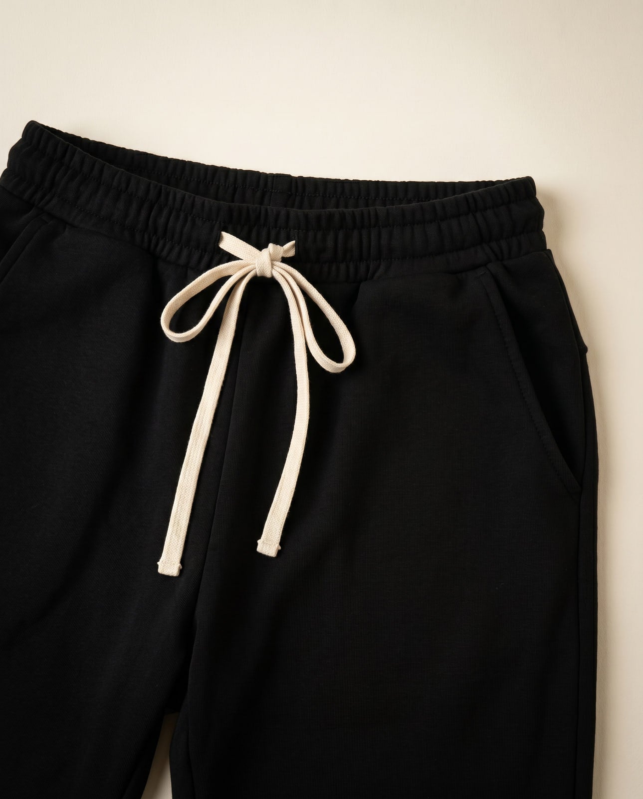 Zoomed detail of the sweatpants waistband, cream drawstring, and side pocket