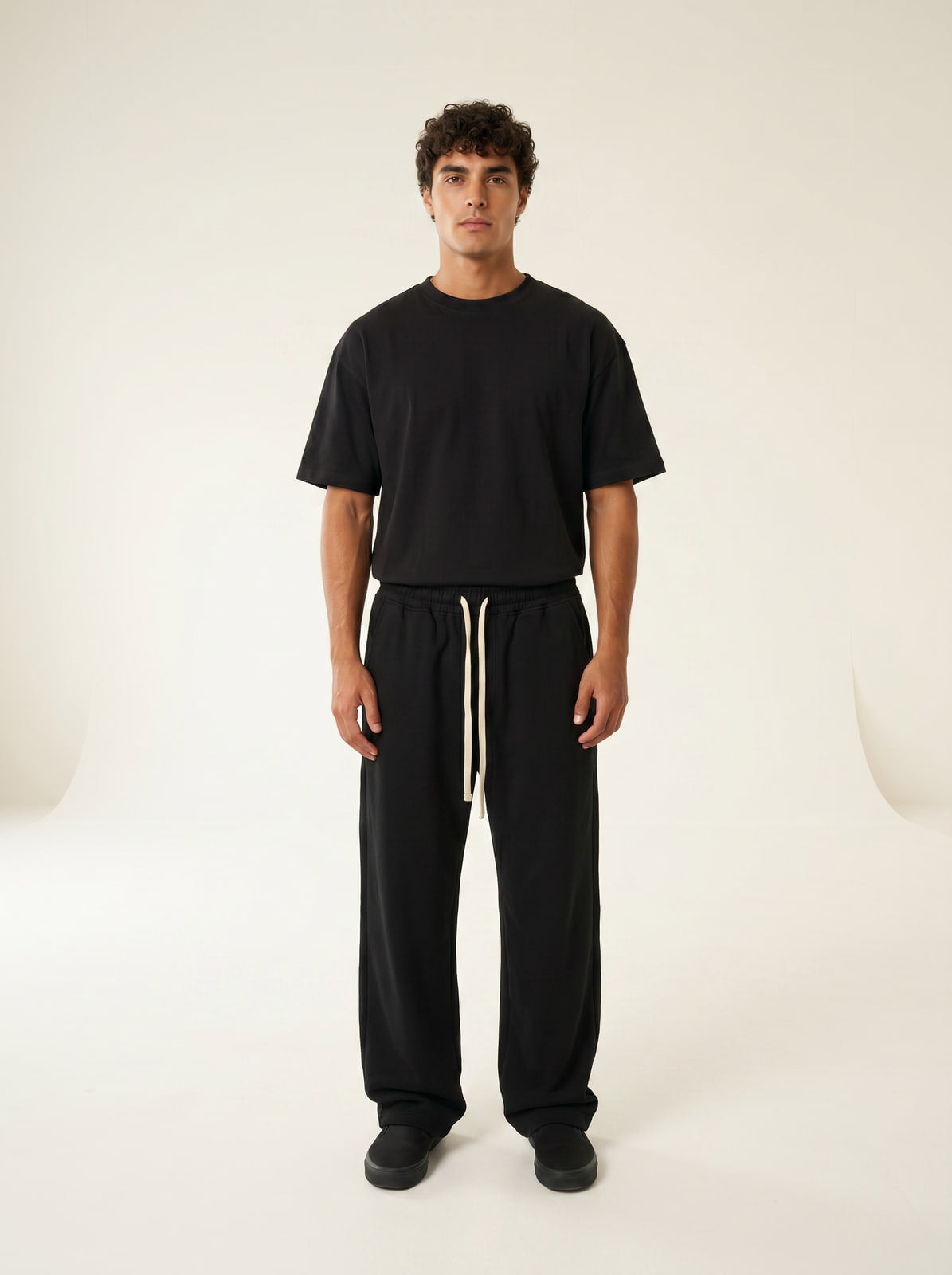 Black wide-leg sweatpants with cream drawstring, front view on model, cream studio