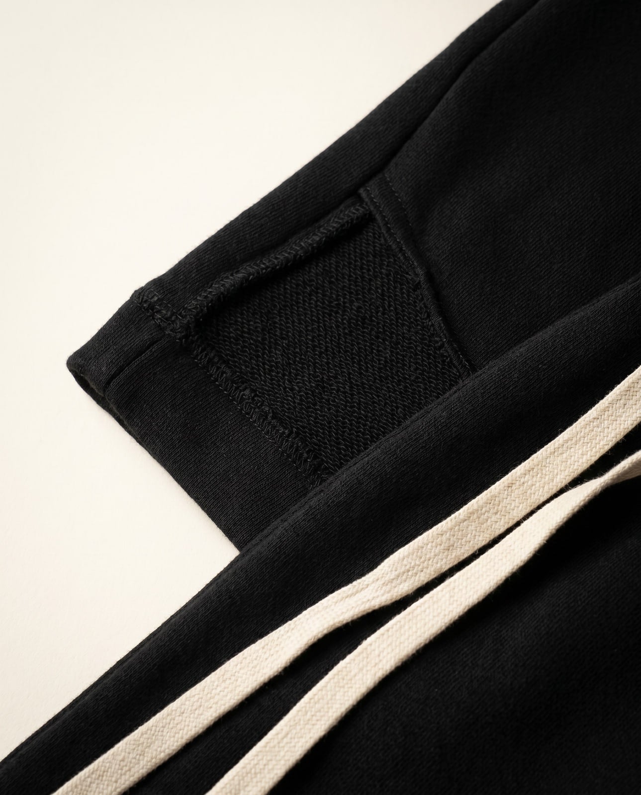 Macro close-up of the black French terry fabric with cream drawstring accent