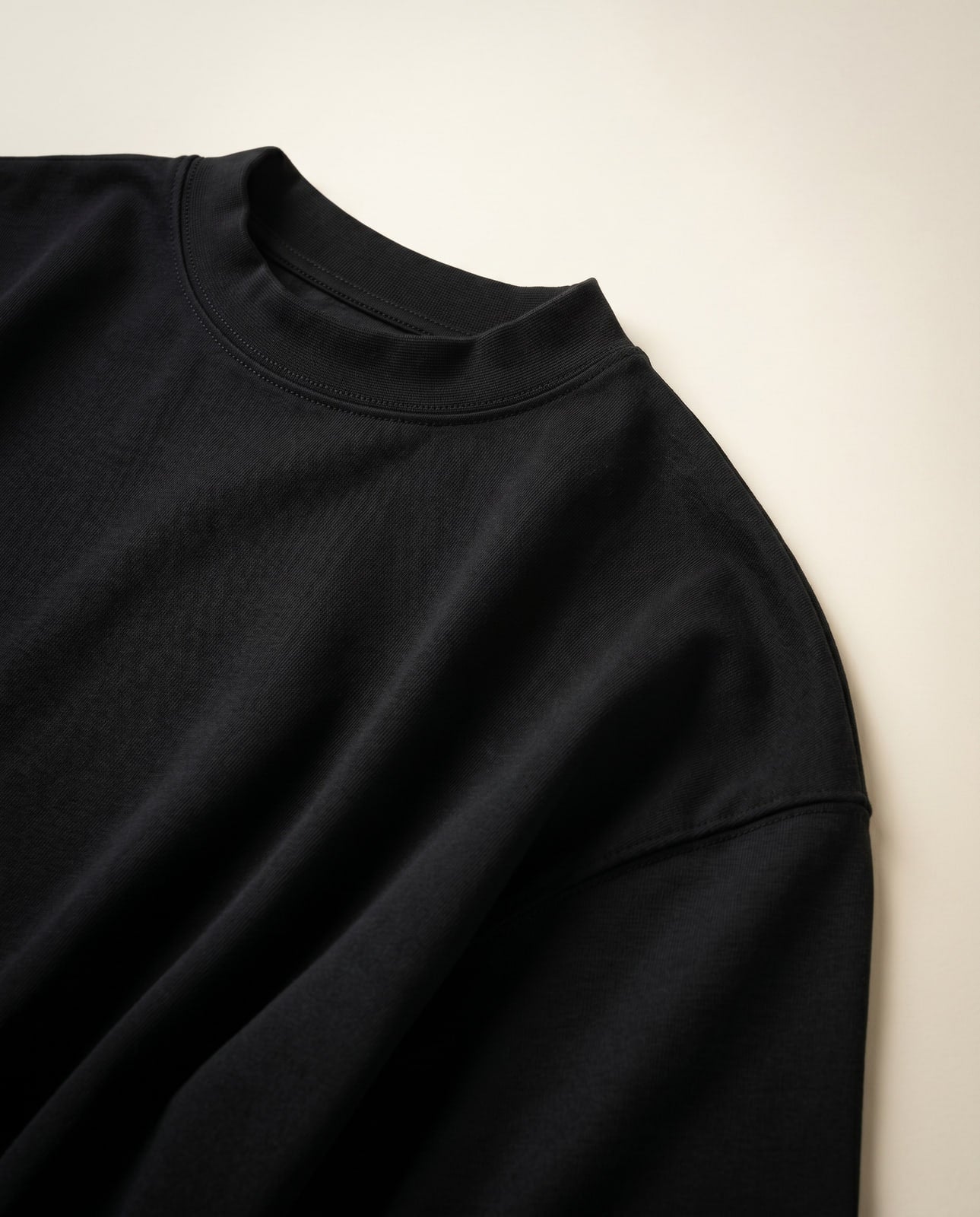 Zoomed detail of the T-shirt's ribbed mock-crew neckband and dropped shoulder seam
