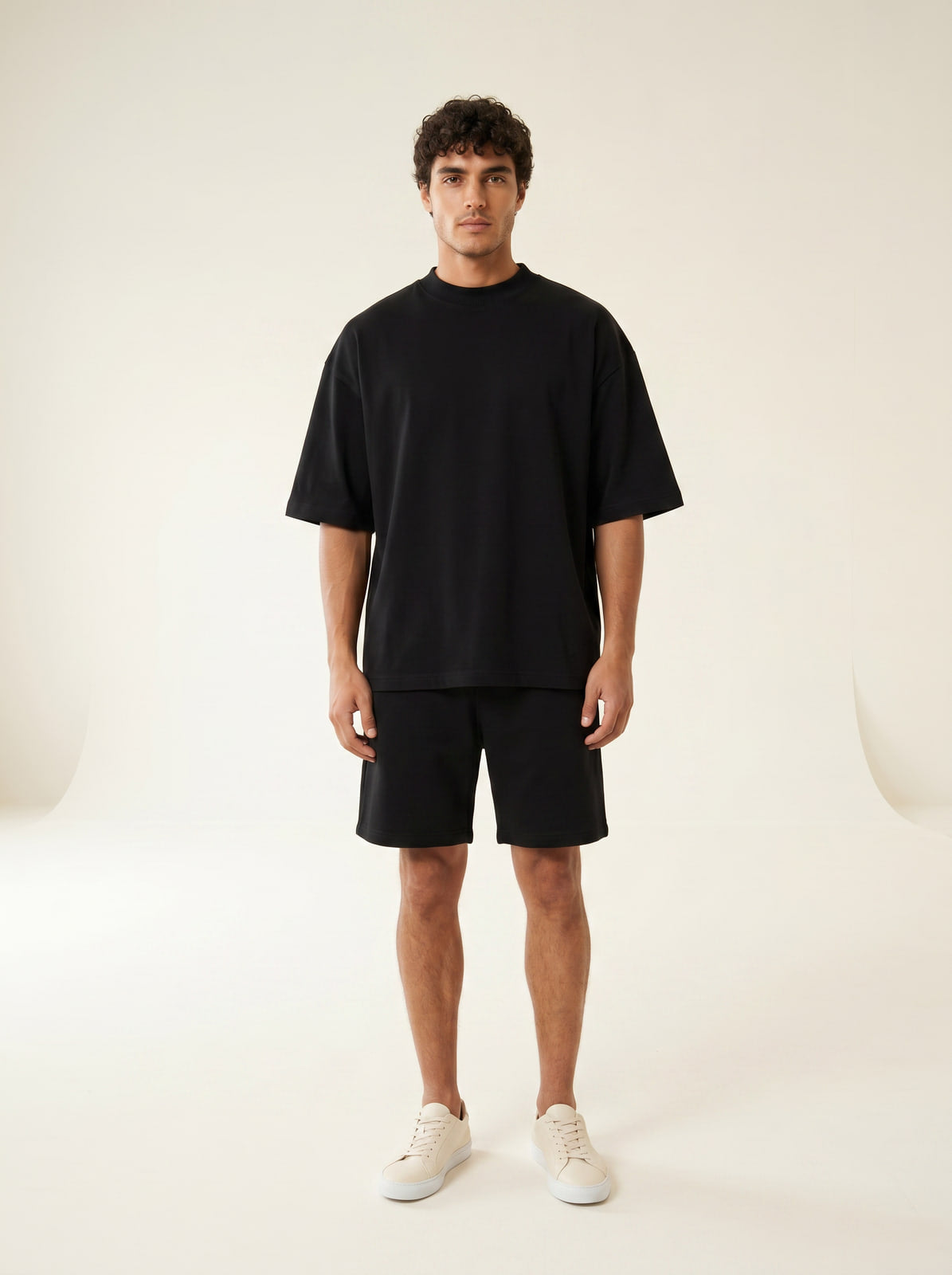 Oversized black heavyweight t-shirt, front view on male model, cream studio