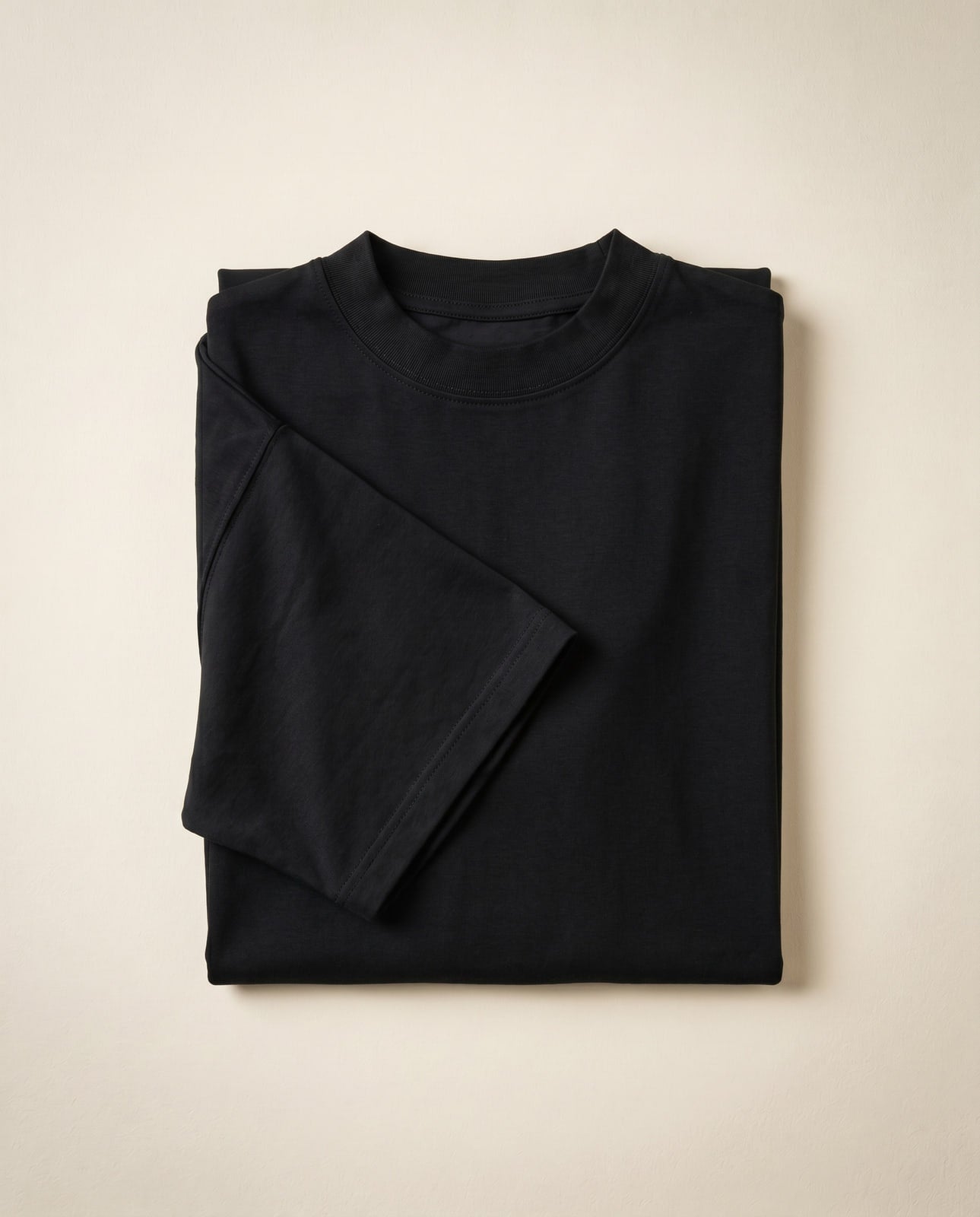 Black heavyweight cotton t-shirt flat lay showing fabric structure, cream surface
