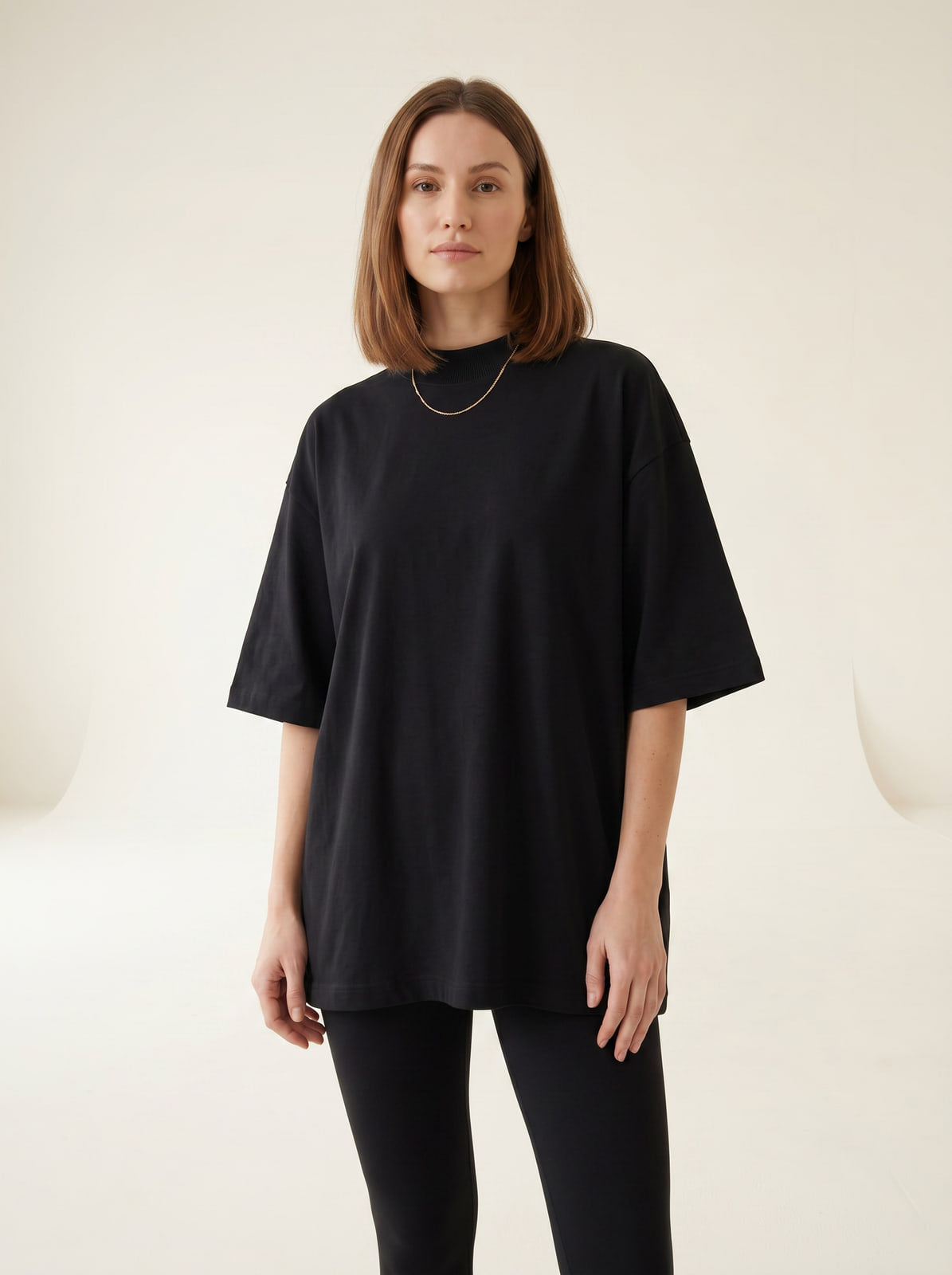 Oversized black heavyweight t-shirt worn loose on female model, cream studio